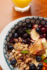 Rich oatmeal with fresh berries, nuts, fruit and peanut butter