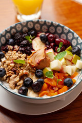 Rich oatmeal with fresh berries, nuts, fruit and peanut butter