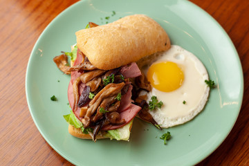 Ciabatta with oyster mushrooms, ham and fried egg for breakfast