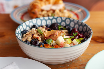 Rich oatmeal with fresh berries, nuts, fruit and peanut butter