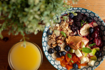 Rich oatmeal with fresh berries, nuts, fruit and peanut butter