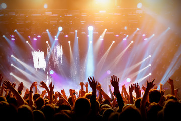 Concert hall with a lit stage and people silhouettes during a concert