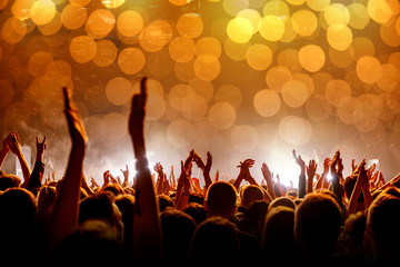 Crowd with raised hands at a concert, light show