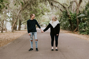 Cute Young Happy Loving Couple Walking Down an Old Abandoned Road with Mossy Oak Trees Overhanging