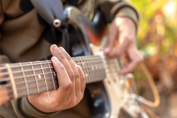 Female hand playing outdoor electric guitar.