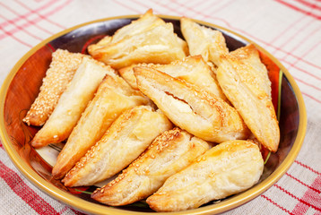 Plate filled with feta cheese triangle appetaizers on a red and white checked tablecloth