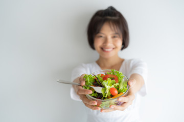 Portrait of asian woman smiling. woman eating salad, focus her hand on white background.