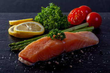 Raw trout with lemon, pepper, tomato on black stone