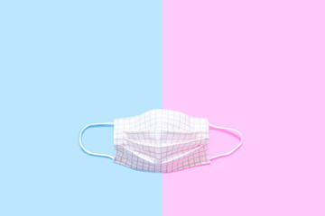 Protective Face Mask Symbol for Dust Protection Sector. Safety Mask (Pink Scotch Pattern) for Air Pollution Street. Single Pink Pastel Medical Mask Isolated on Pink & Blue Color Background.