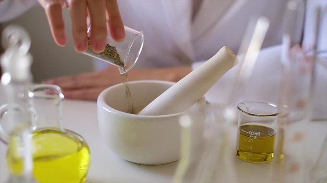 the scientist  doctor is making natural  herb medicine or cosmetic in the laboratory. pour  herbal  in the mortar . on table with  organic cbd oil . skincare health product industry .closeup