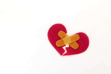 Broken red heart symbol with medical patch on white background, love concept