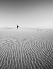 Figure lost in the sand dunes walking off into the distance alone