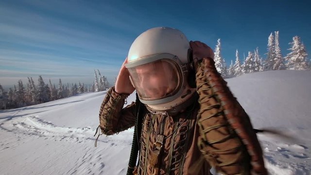 Pilot astronaut is on a snow-capped top. Astronaut in a protective suit and helmet.