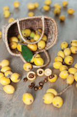 The above view of the basket with loquat, asian fruit, and its seeds on the wooden background