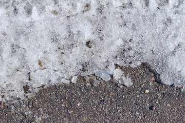 Macro abstract view of grungy melting snow on an asphalt surface