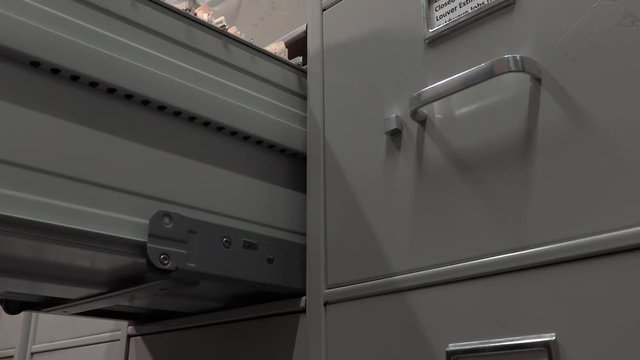 Office Worker Opening a File Cabinet in a File Storage Room.