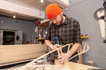 Home repair concepts, close up. Handicraft Carpentry. Cabinet-maker hands drilling a wooden plank using turn-screw on the working table in the workshop