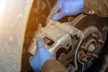 Close up Professional car mechanic changing front brake pads in auto repair service. Autoworker repair brakes in garage of repair service station