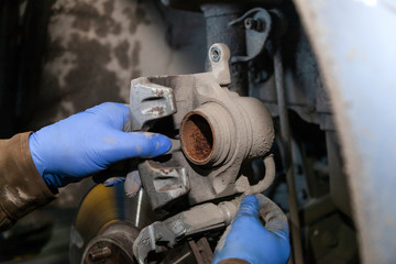 Close up Professional car mechanic changing front brake pads in auto repair service. Autoworker repair brakes in garage of repair service station