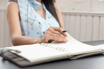 Freelancer business woman holding pen and notebook in cafe.