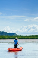 Fototapeta na wymiar Man draging kayak on mud land of Tung Yee Peng mangrove. Krabi - Thailand