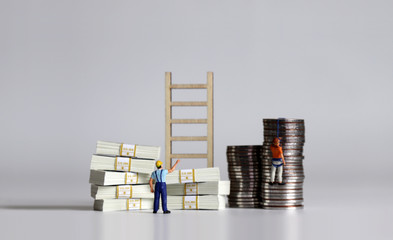 Pile of bills and coins. Miniature people and wooden ladders.