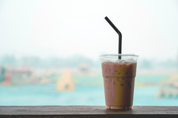 Ice coffee on a wooden table at abstract blurred background.