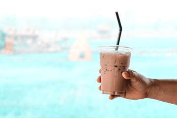 Hand holding Ice coffee at abstract blurred background.