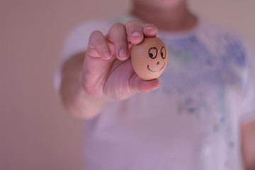 A man holding an egg with a funny face. Conceptual image