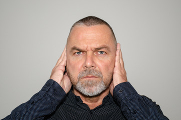 Determined man covering his ears with his hands