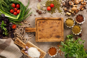 Fresh greens and tomatoes spices cereals and nuts organic healthy snacks on a textural background. Concept of healthy food. Decorative board. Frame under the text.