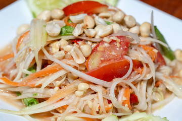Green papaya salad or Som tum Thai in white plate, closeup. Thai cuisine, somtum salad popular food in Thailand