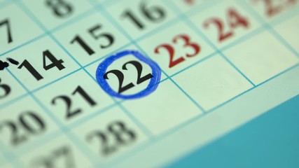 22. The twenty-second day of the month. Marking the date in the calendar with a blue marker