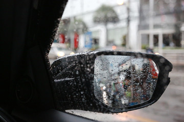 Raindrops on car rear view mirror outside.
