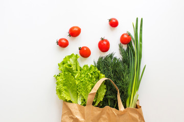  fresh vegetables and greens in a paper bag on a white background