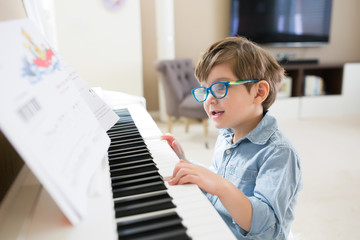 Toddler boy is concentrated on piano and musical notes © ipek