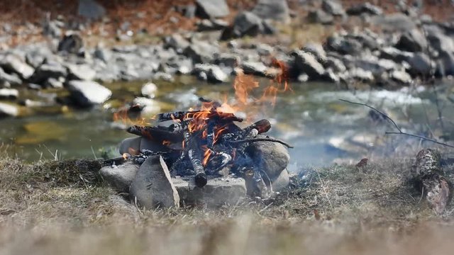 Burning campfire on the side of the river.