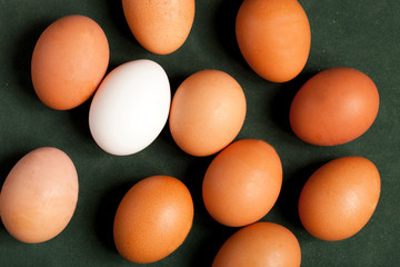 Close-up view of raw chicken eggs in box, egg white, egg brown on green background