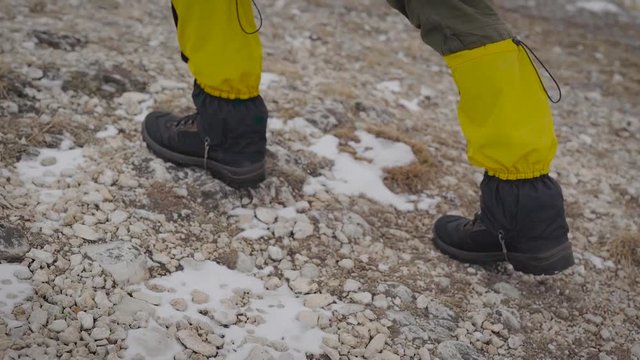 male tourist is walking in mountains in daytime, close-up view of feet shod in special protective shoes