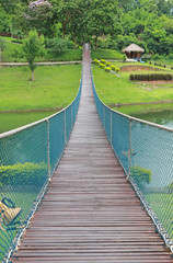 Wooden rope suspension bridge for walk crossing river.