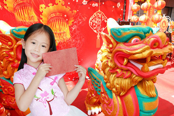 Happy little Asian child girl wearing pink traditional cheongsam dress smiling while receiving red envelope packet on chinese festival background. Happy chinese new year concept.