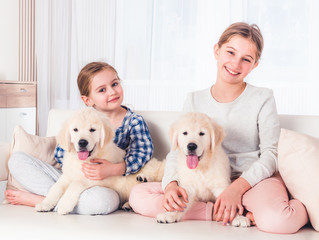 Smiling sisters sitting with puppies