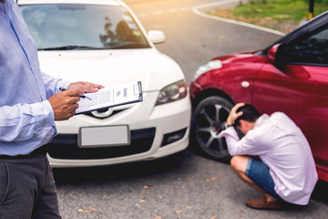 Fototapeta na wymiar Insurance agent writing on clipboard while examining car after accident claim being assessed and processed.