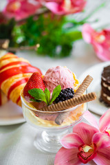 ball of pink ice cream in a glass with berries and biscuits