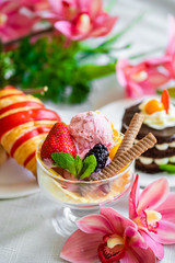 ball of pink ice cream in a glass with berries and biscuits