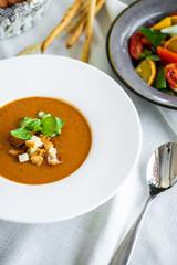 Mexican lunch, gazpacho soup with crackers and hot peppers in a white plate. tomato soup with vegetables. mexican soup. Puree soup tomato with croutons. Diet menu. tomato soup in a white plate