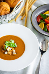 Mexican lunch, gazpacho soup with crackers and hot peppers in a white plate. tomato soup with vegetables. mexican soup. Puree soup tomato with croutons. Diet menu. tomato soup in a white plate