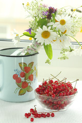 A bouquet of wildflowers and a glass bowl of red currant	