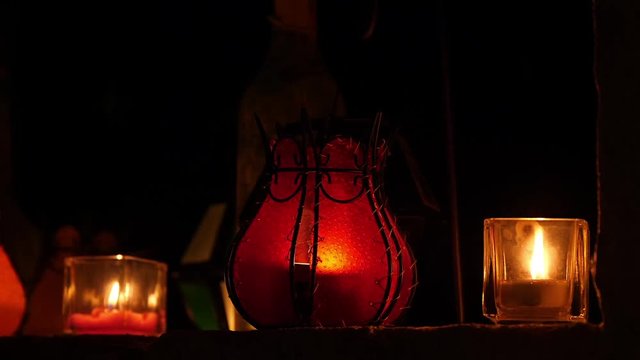 Lichter und Kerzen flackern in einem offenen Fenster eines alten Bauernhauses