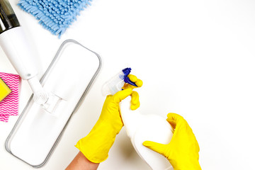 Housework, housekeeping, household, cleaning service concept. Cleaning spray mop, rags, sponges and woman hands in rubber gloves with detergent spray bottle on white background